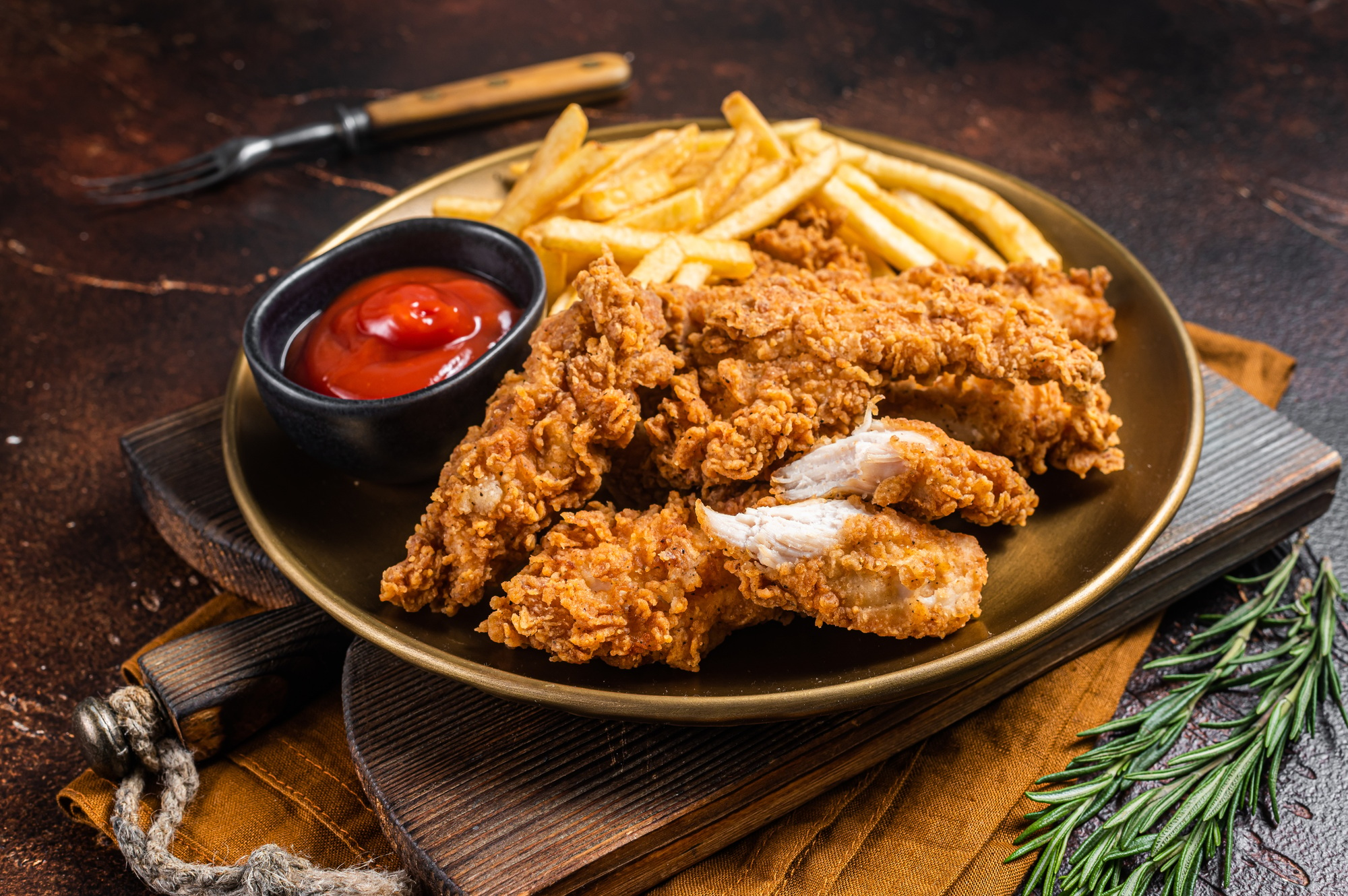 Fried Breaded chicken tender strips with french fries and tomato ketchup on a plate.